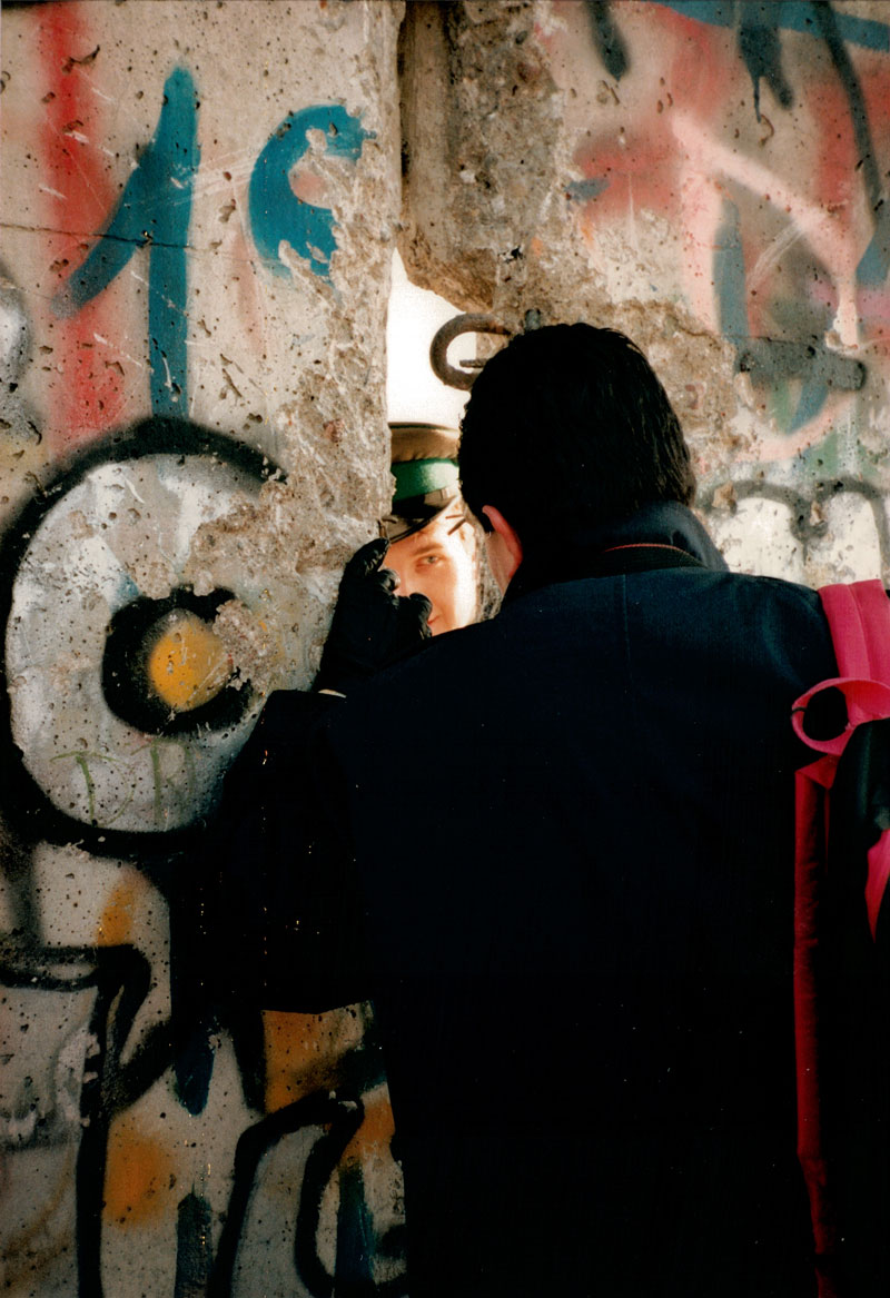 Two German men greet each other through a hole in the Berlin wall.