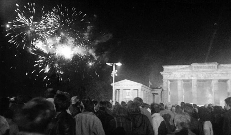 A black and white photo of a crowd of demonstrators with fireworks in the night sky.