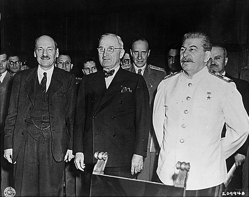 A black and white photo of British Prime Minister Clement Attlee, US President Harry S. Truman, and Soviet leader Josef Stalin.