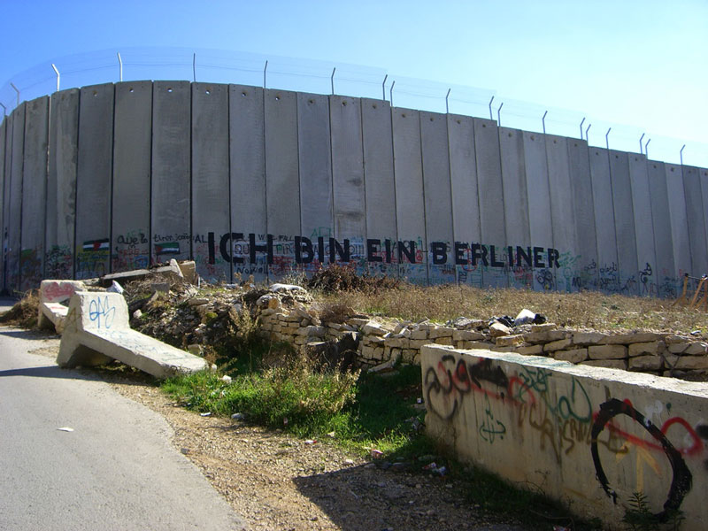 A section of the Israel/West Bank barrier wall with 'Ich bin ein Berliner' written in graffiti.