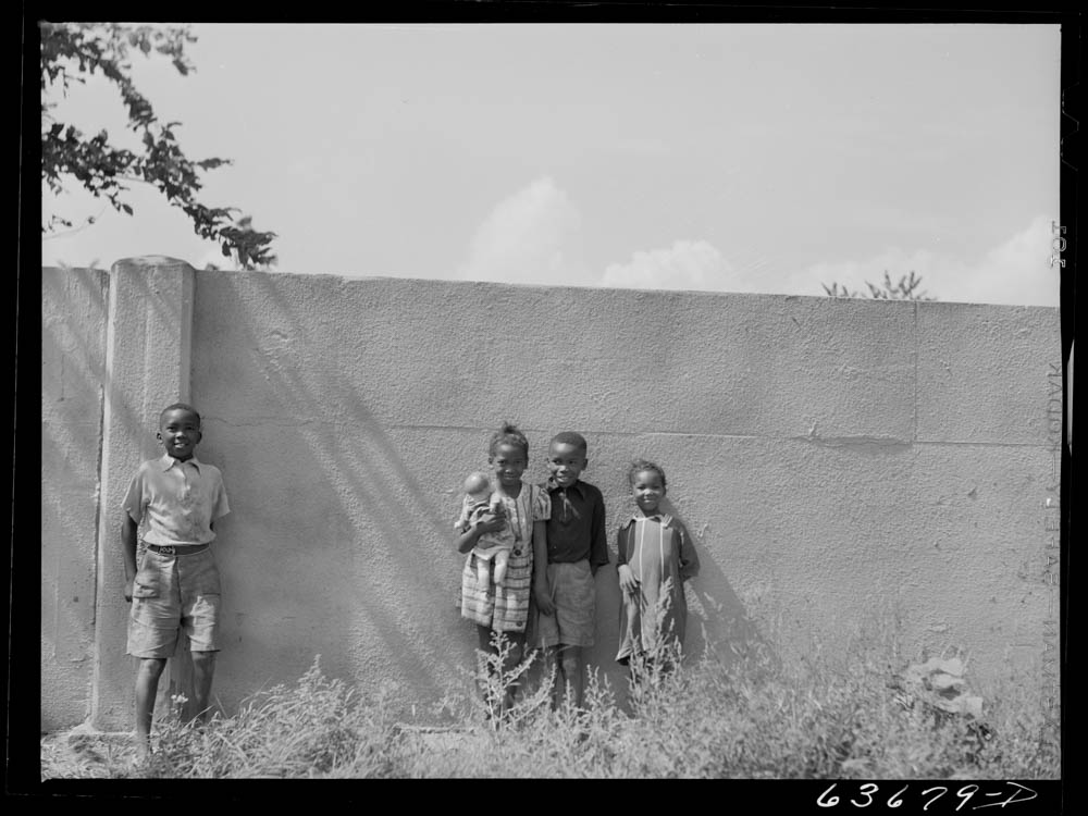 Four children posing in front of a wall.